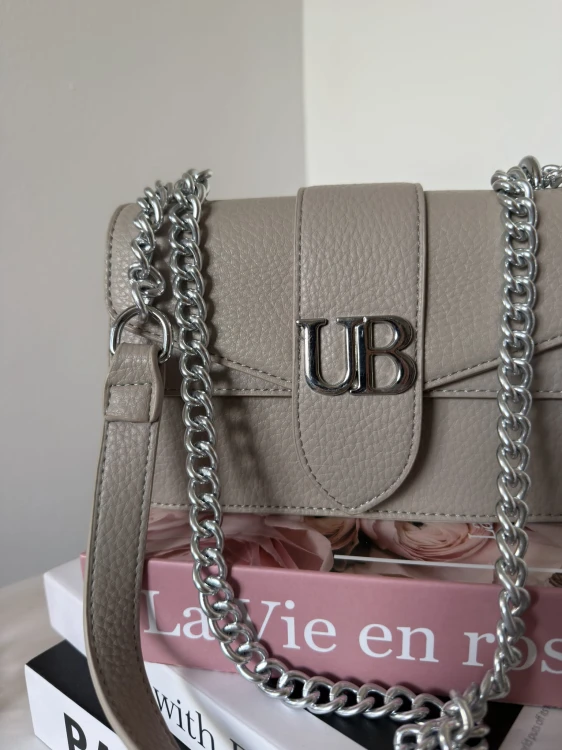Zbliżenie na logo UB i srebrny łańcuszek – torebka Unibella taupe